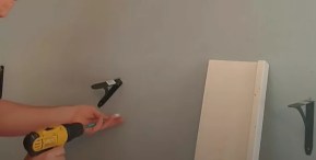 man using a cordless drill to put up shelves