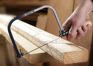 man using a coping saw to cut wood