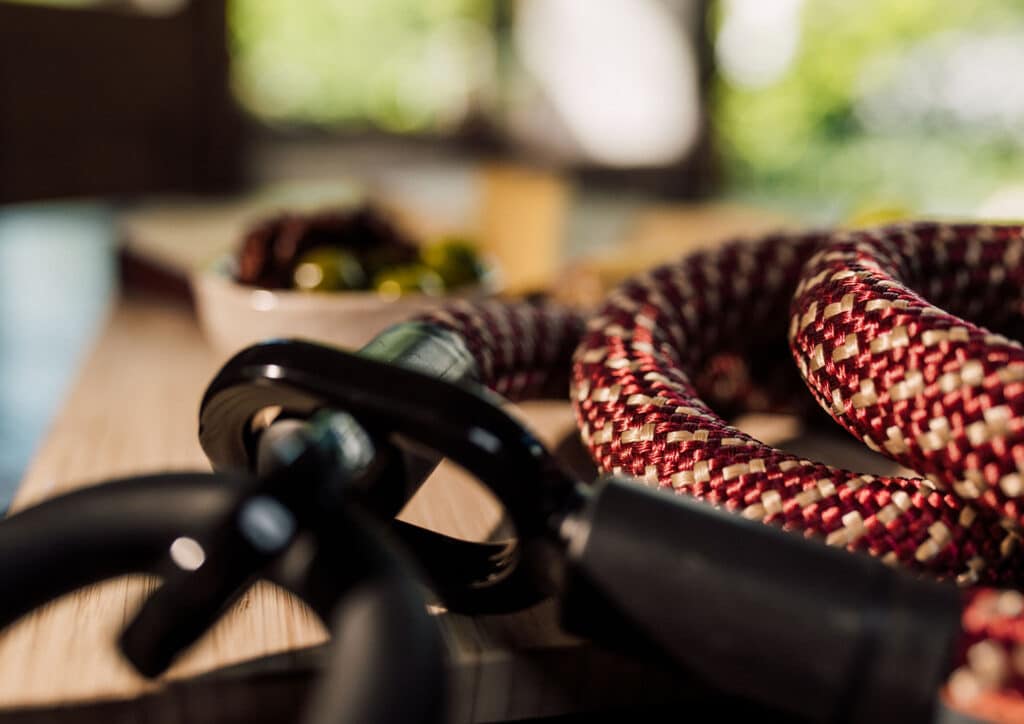 Nahaufnahme des tex–lock eyelet in chateau red mit Bügelschloss auf einem Holzbrett mit Antipasti im Hintergrund