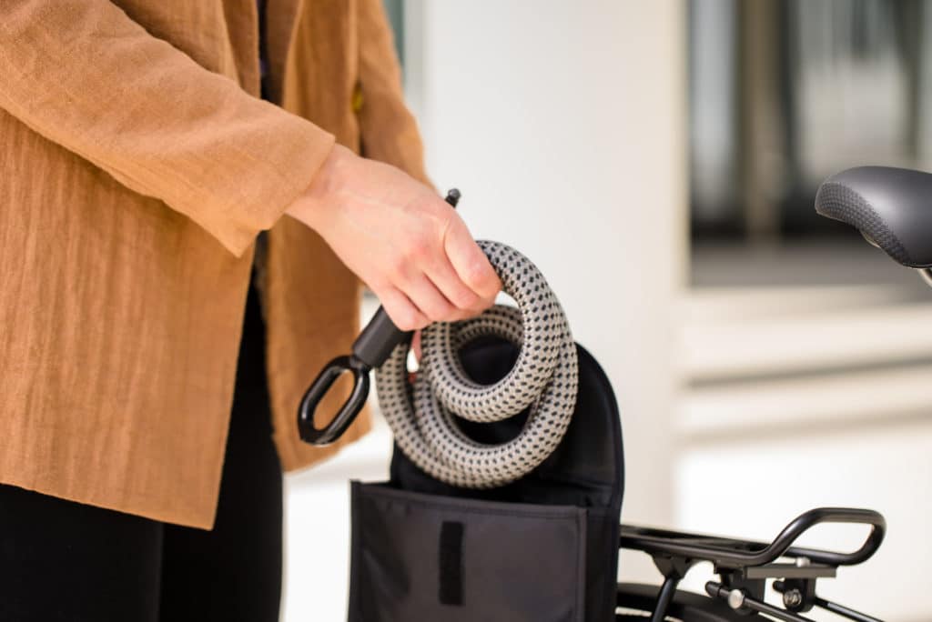 Frau holt flexible Rahmenschloss-Verlängerung tex-lock mate in grau aus schwarzer kleiner Tasche