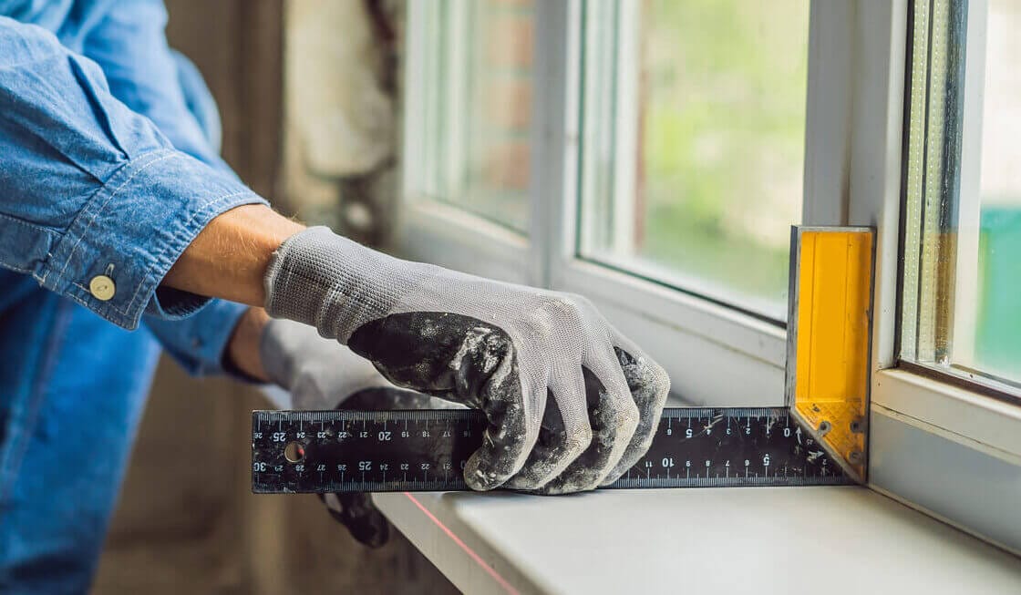 A person measuring a window while installing