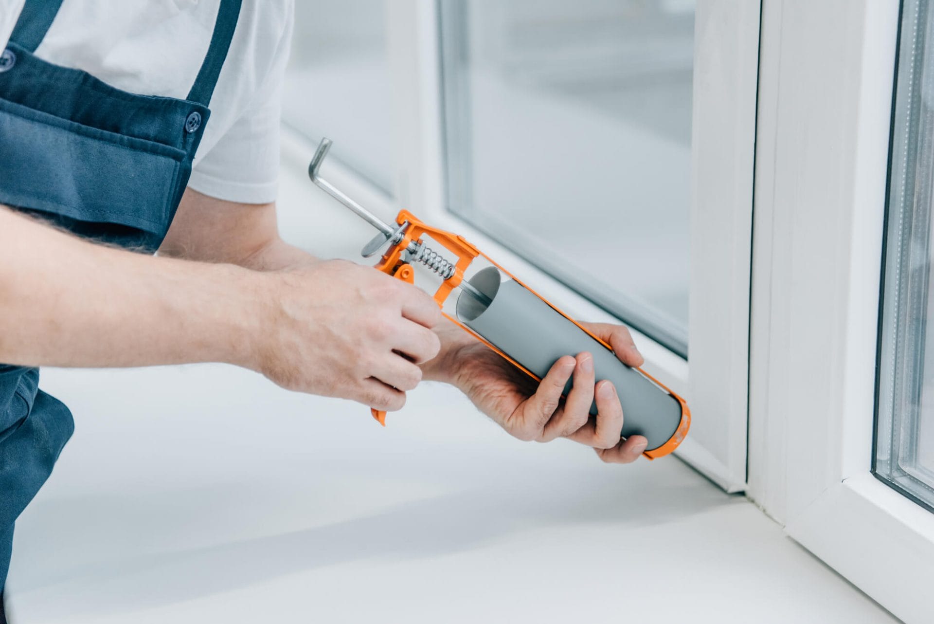 A window expert repairing a window with caulking gun